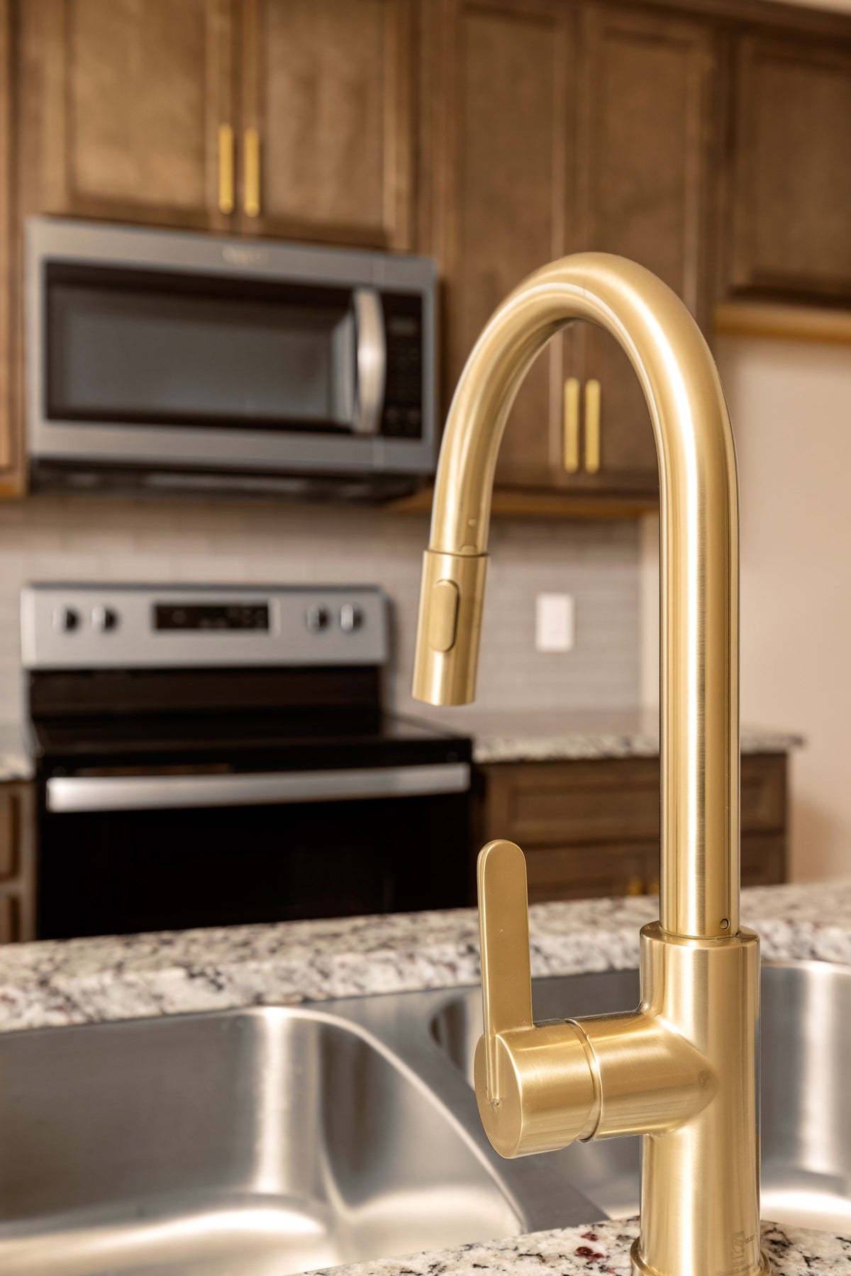 Brushed gold pull-down kitchen faucet over a stainless sink